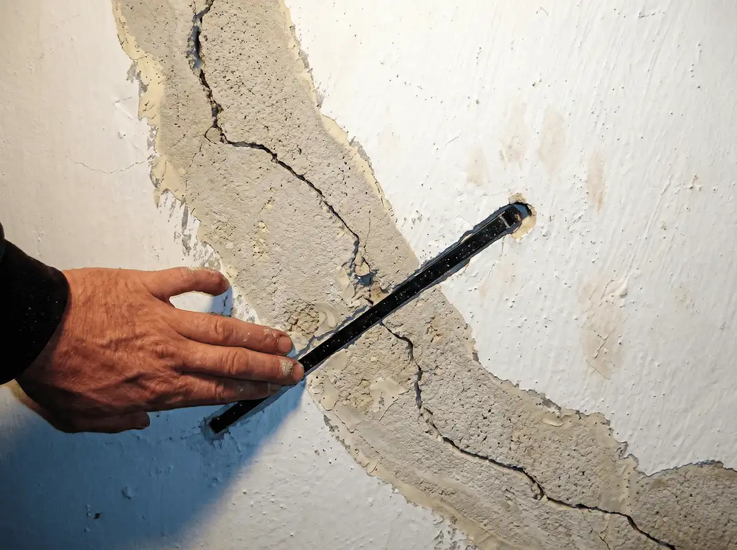A wall with a large crack is being inspected by a professional in Atlanta, GA